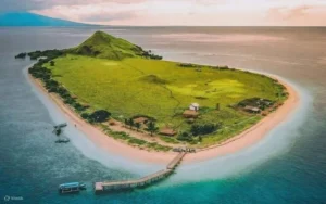 Aerial view of Kanawa Island with green hills and clear waters, ideal for snorkeling.